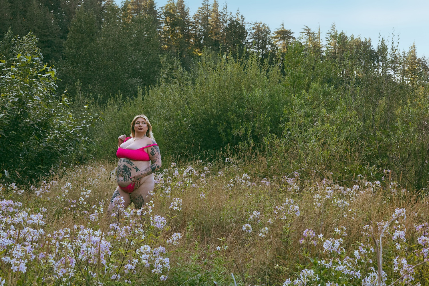 boudoir photo of a plus size woman standing in a field of wildflowers